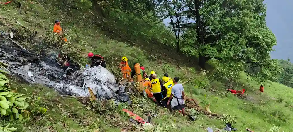 Rescue team and NDRF officials at the Kedarnath Helicopter Crash site on a forested hillside with visible wreckage and debris.